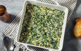 Creamy Spinach Artichoke Dip in a white square pan on a gray table